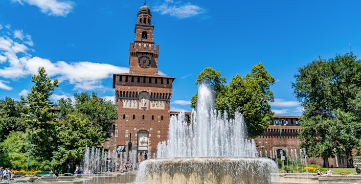 Fountain in front of Sforza Castle, Milan, with clock tower and trees.