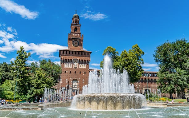 Fountain in front of Sforza Castle, Milan, with clock tower and trees.