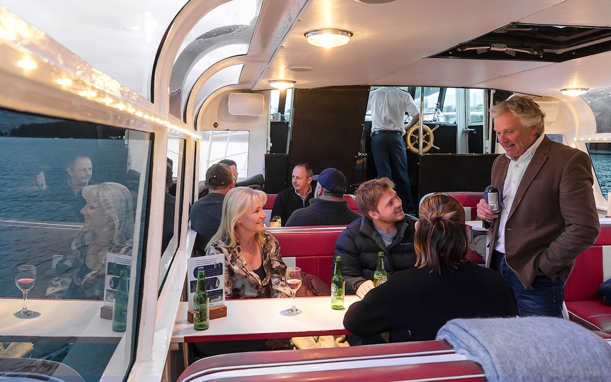 Passengers socializing in the indoor cabin of a boat on Lake Wakatipu cruise, Queenstown, New Zealand.
