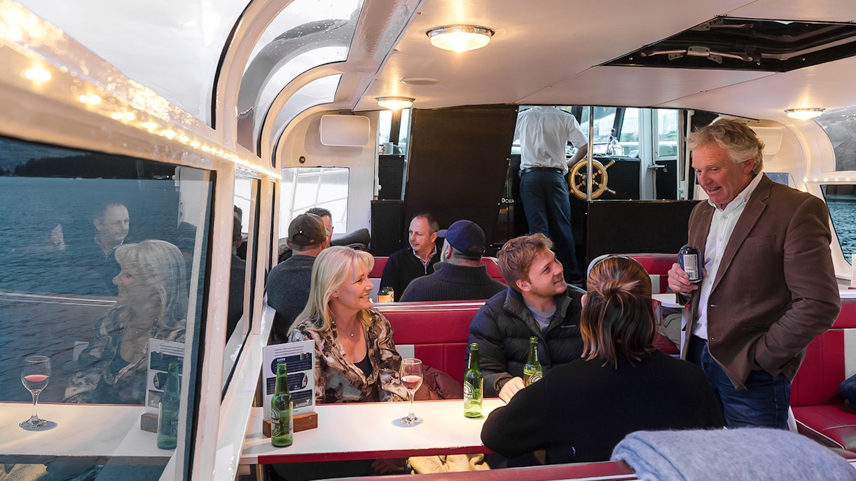 Passengers socializing in the indoor cabin during a Lake Wakatipu cruise, Queenstown, New Zealand.