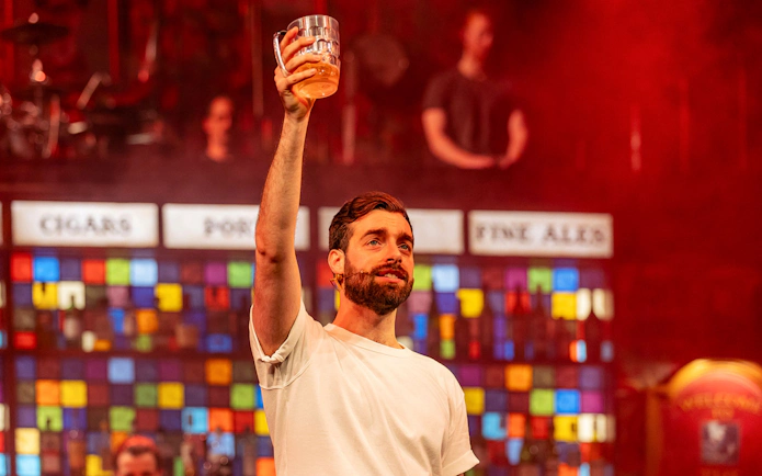 Performer holding a beer mug on stage during The Choir of Man show.