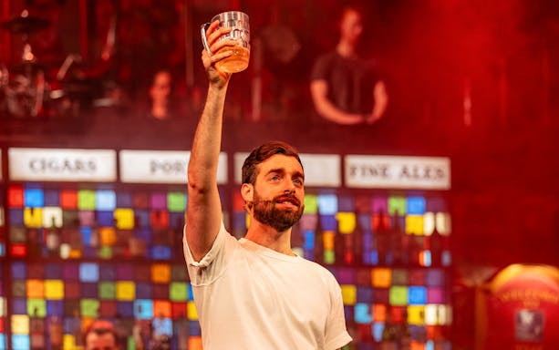 Performer holding a beer mug on stage during The Choir of Man show.