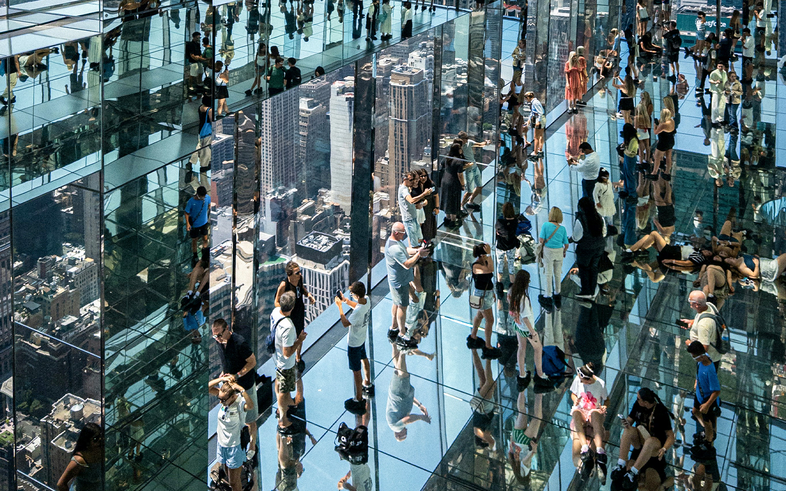 Visitors walking on glass floors at SUMMIT One Vanderbilt, New York City, with skyline reflections.