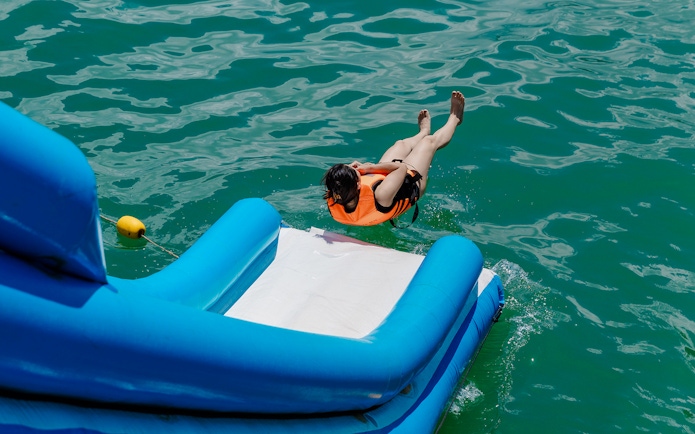 Person sliding off inflatable pool slide into water.