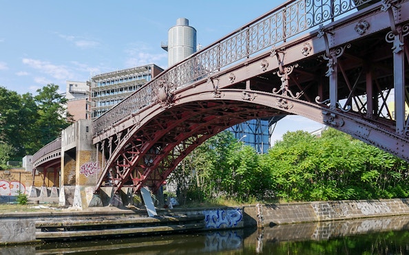 Anhalter Steg bridge over Landwehr Canal in Berlin with surrounding greenery.