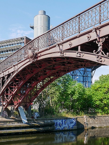 Anhalter Steg bridge over Landwehr Canal in Berlin with surrounding greenery.