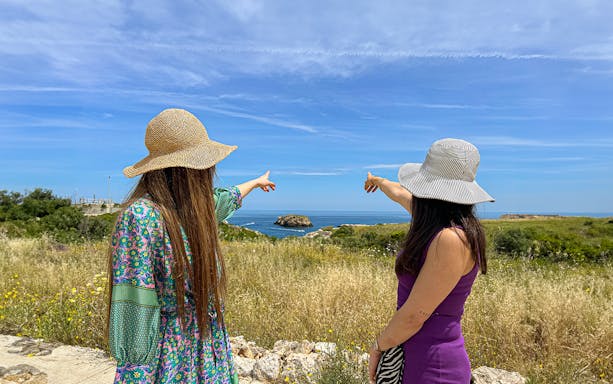 Two people pointing towards the sea on a coastal tour in Polignano a Mare.