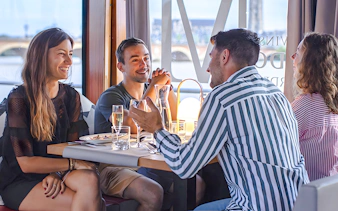 Group enjoying lunch on Bateaux Bordelais cruise with river view in Bordeaux.