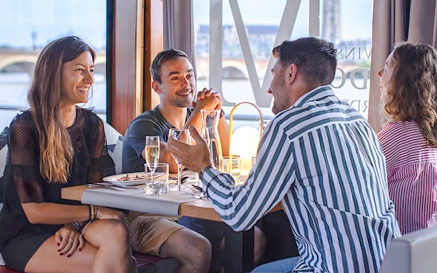 Group enjoying lunch on Bateaux Bordelais cruise with river view in Bordeaux.