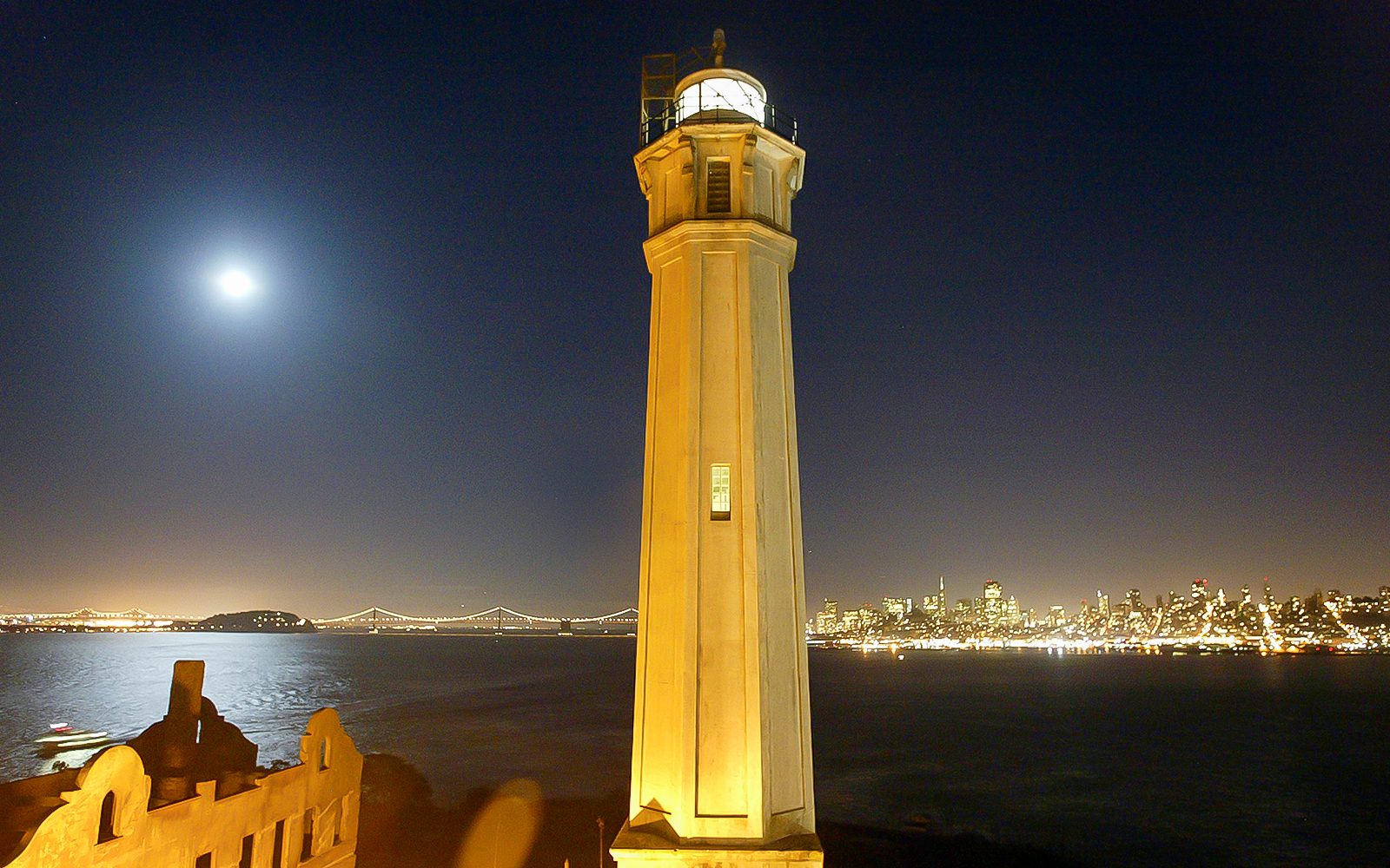 Alcatraz Island lighthouse with San Francisco skyline at night.