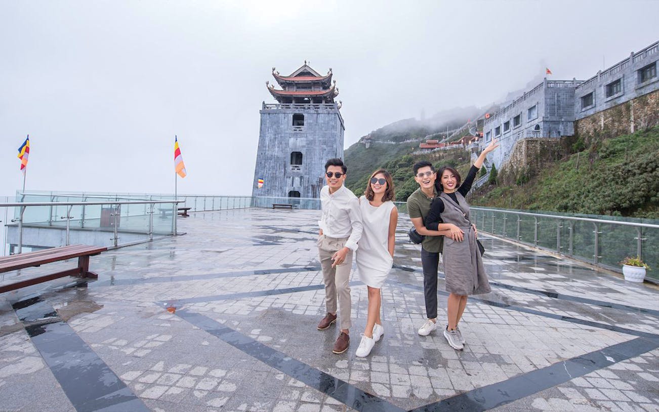 Group enjoying Sun World Fansipan with pagoda and misty mountain backdrop.
