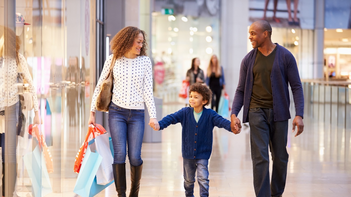 Family walking through a mall with shopping bags.