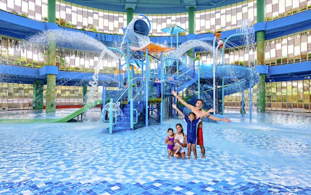 Family enjoying water park with slides and fountains in Singapore.