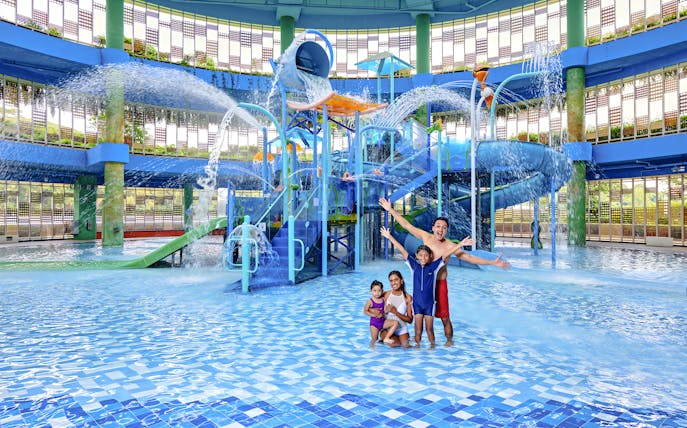 Family enjoying water park with slides and fountains in Singapore.