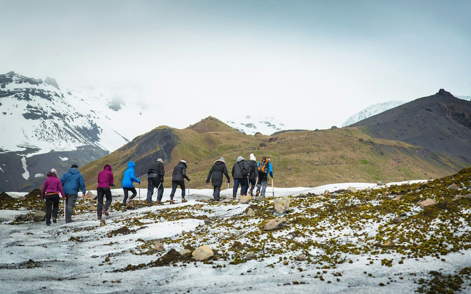 Group hiking on Vatnajökull Glacier, Iceland, with snowy mountains in the background.