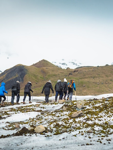 Group hiking on Vatnajökull Glacier, Iceland, with snowy mountains in the background.