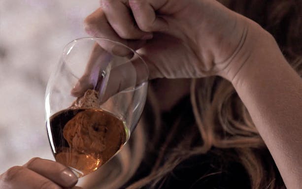 Wine expert examining a glass of Super Tuscan wine during a masterclass.