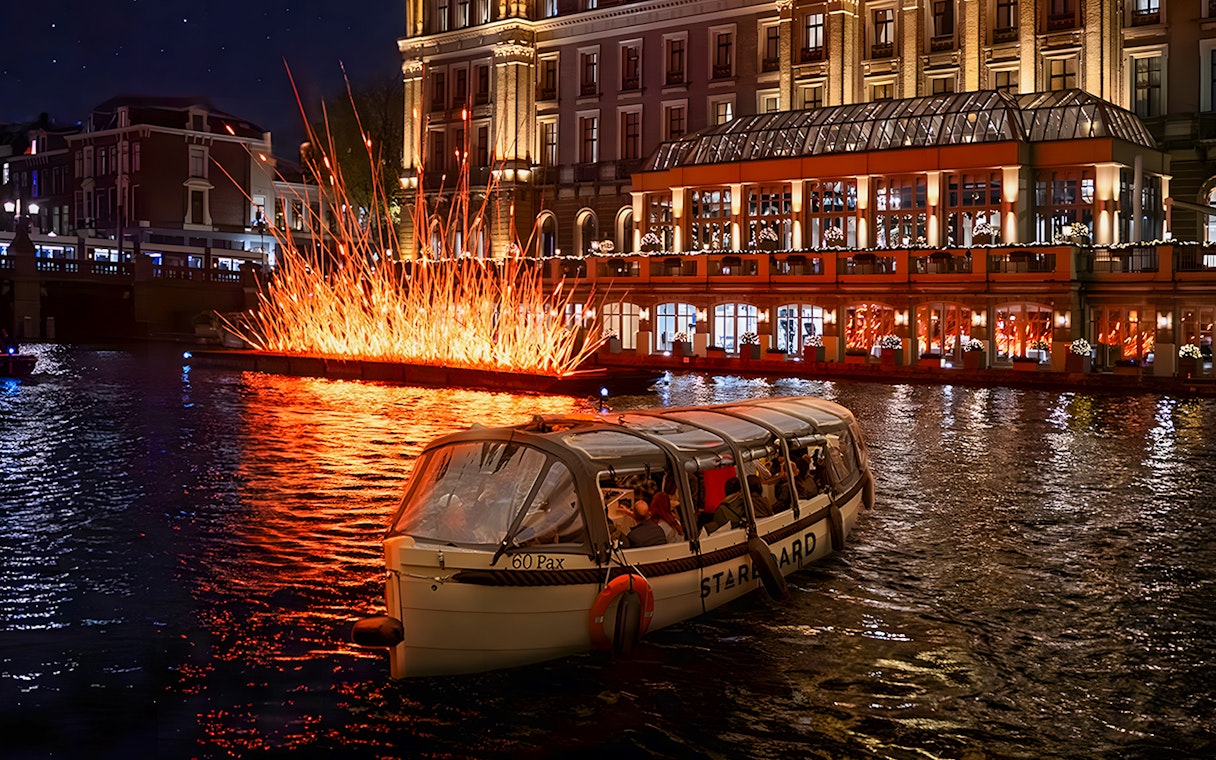 Amsterdam canal cruise passing illuminated art installation during Light Festival.