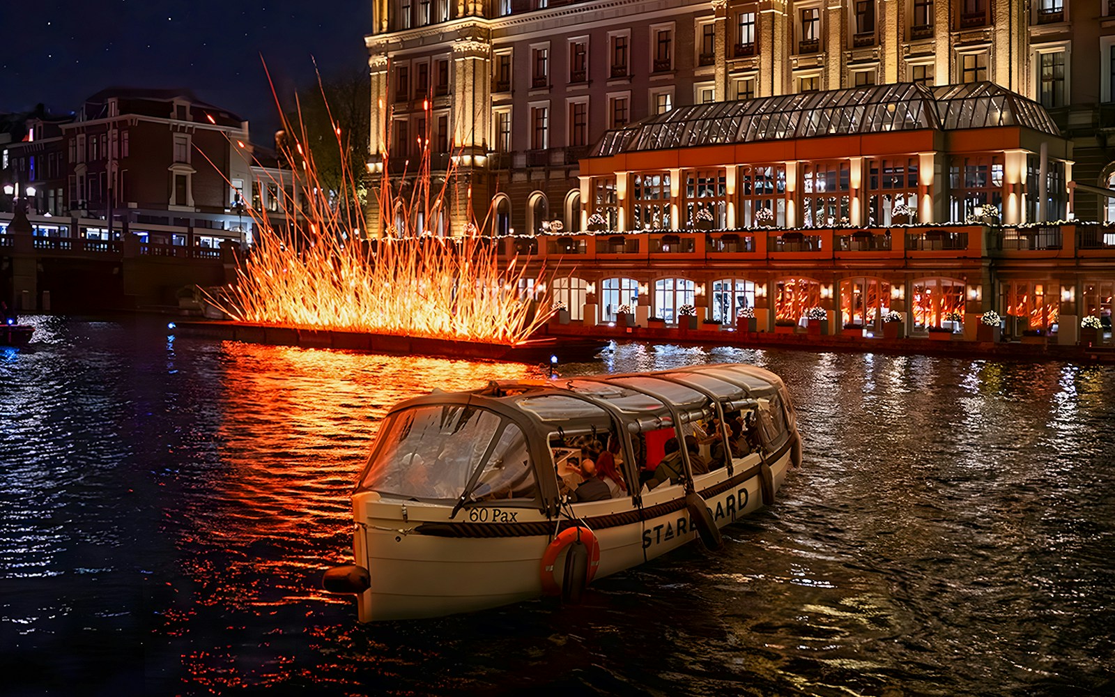 Amsterdam canal cruise during Light Festival with illuminated art installations, featuring unlimited drinks and snacks option.