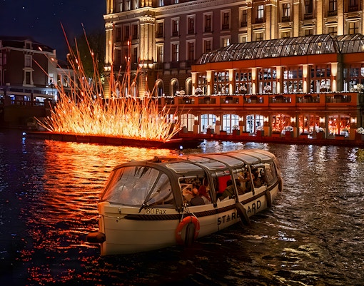 Amsterdam canal cruise passing illuminated art installation during Light Festival.