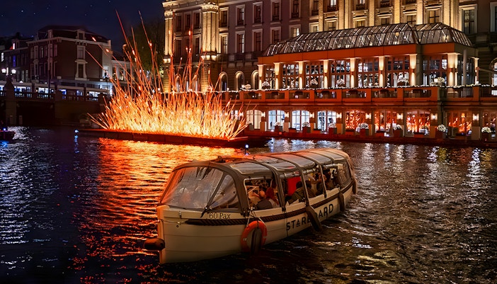 Amsterdam canal cruise passing illuminated art installation during Light Festival.