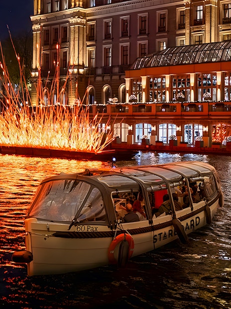 Amsterdam canal cruise passing illuminated art installation during Light Festival.