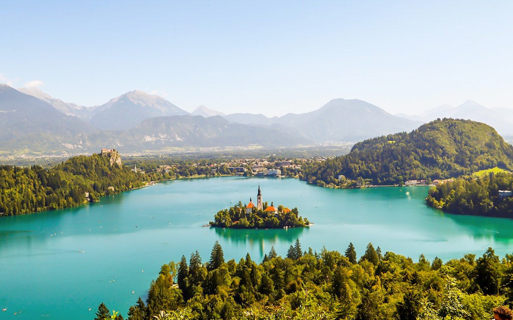 Church of the Assumption of Mary on Bled Lake, Slovenia, surrounded by mountains.