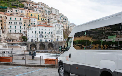 Van parked along the Amalfi Coast with hillside buildings in the background.