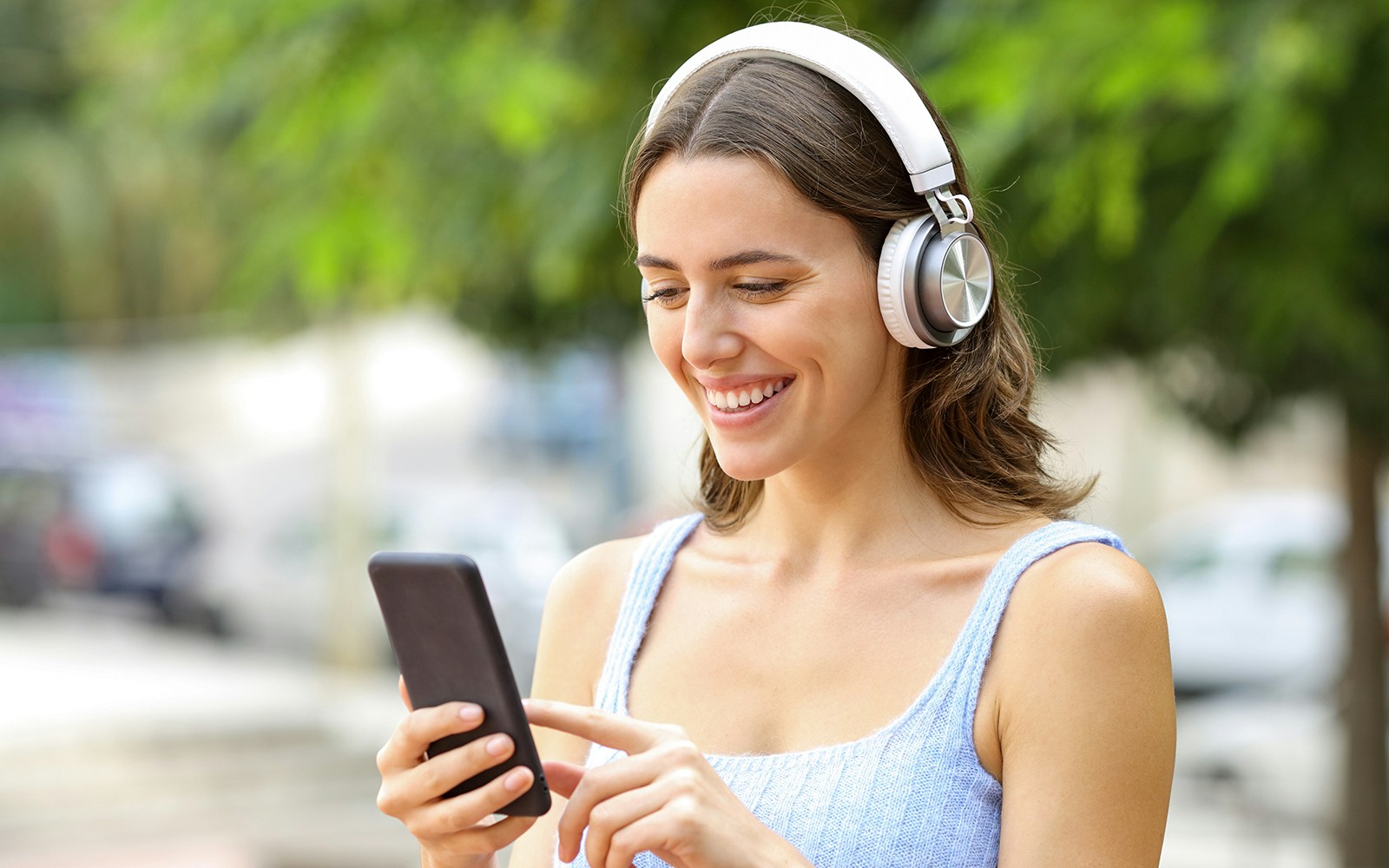 Woman using smartphone audio guide with headphones outdoors.