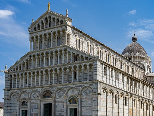 Cathedral of Pisa with tourists outside, featuring its ornate facade and dome.