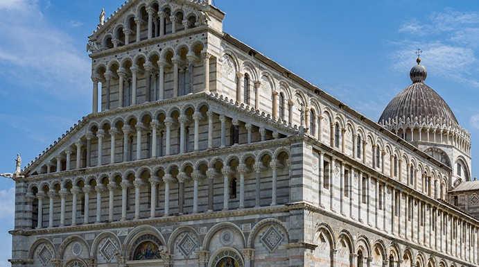 Cathedral of Pisa with tourists outside, featuring its ornate facade and dome.