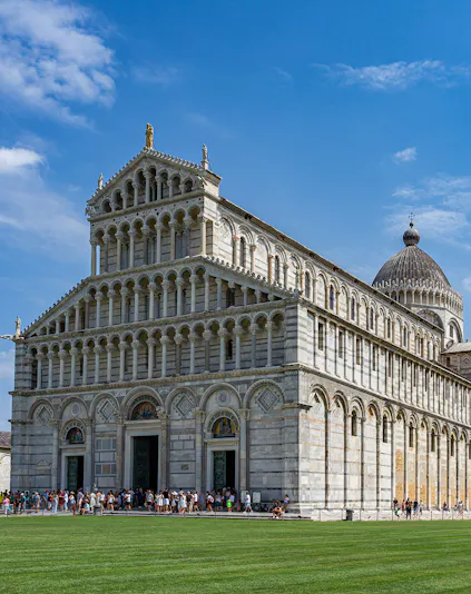 Cathedral of Pisa with tourists outside, featuring its ornate facade and dome.