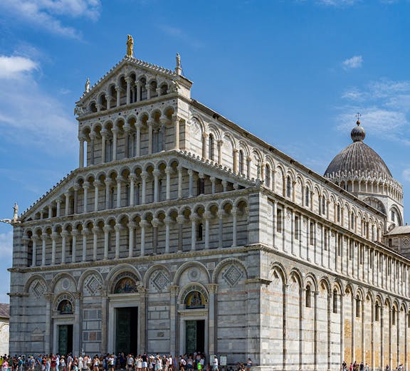 Cathedral of Pisa with tourists outside, featuring its ornate facade and dome.