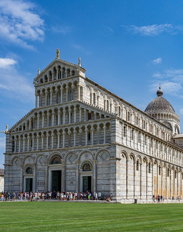 Cathedral of Pisa with tourists outside, featuring its ornate facade and dome.