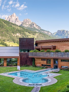 Outdoor pool at QC Terme Dolomiti with mountain view in the background.