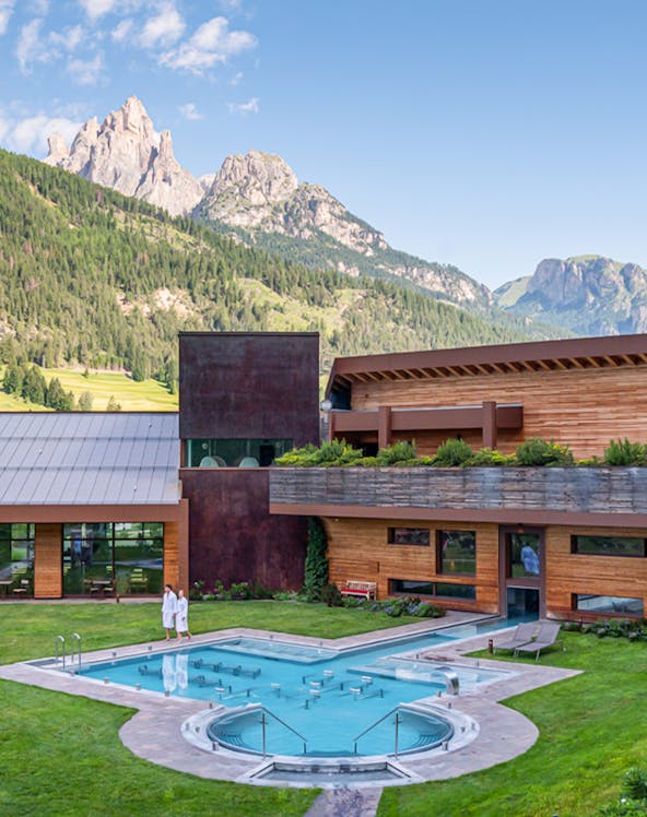 Outdoor pool at QC Terme Dolomiti with mountain view in the background.
