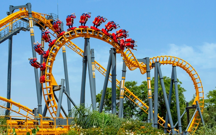 Isla Mágica roller coaster with riders on a loop against a clear sky.