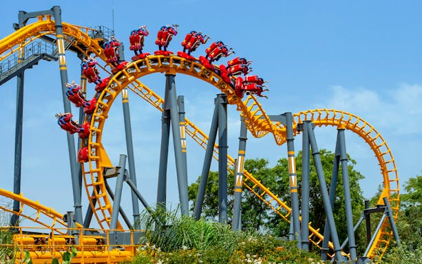 Isla Mágica roller coaster with riders on a loop against a clear sky.