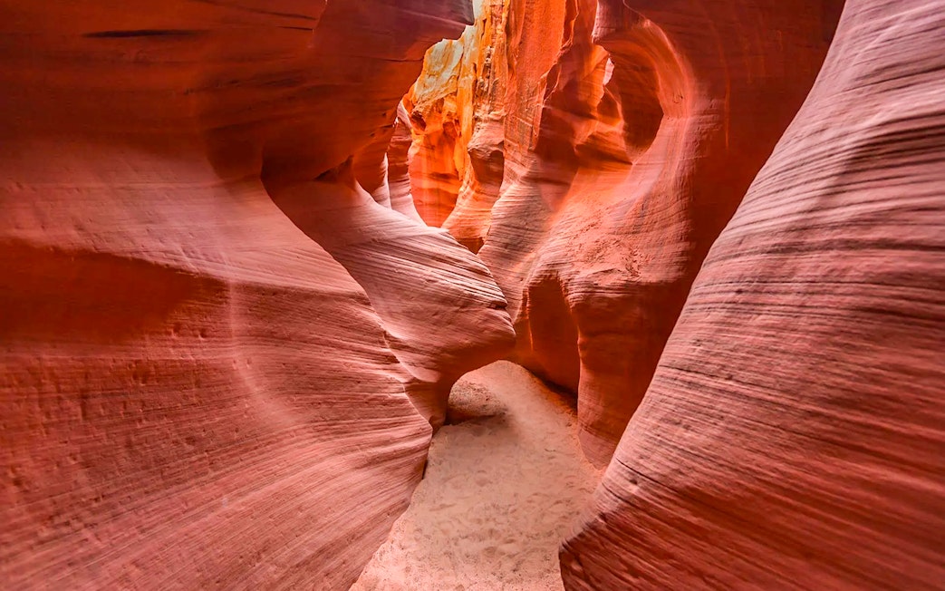 Narrow passage in Secret Antelope Canyon with smooth, red sandstone walls.