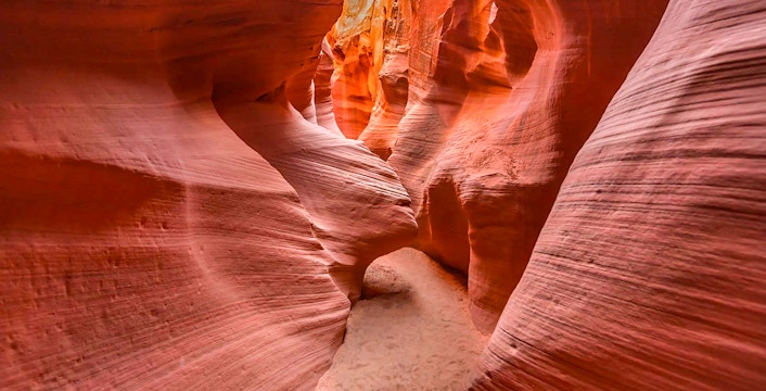 Narrow passage in Secret Antelope Canyon with smooth, red sandstone walls.