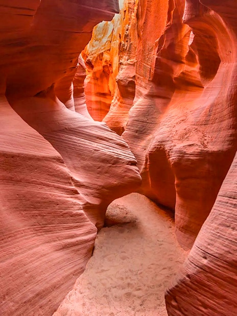 Narrow passage in Secret Antelope Canyon with smooth, red sandstone walls.