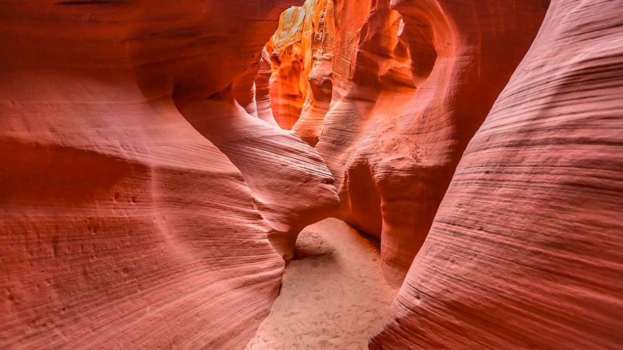 Narrow passage in Secret Antelope Canyon with smooth, red sandstone walls.
