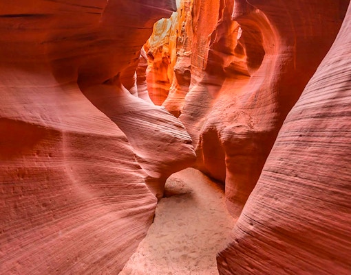 Narrow passage in Secret Antelope Canyon with smooth, red sandstone walls.