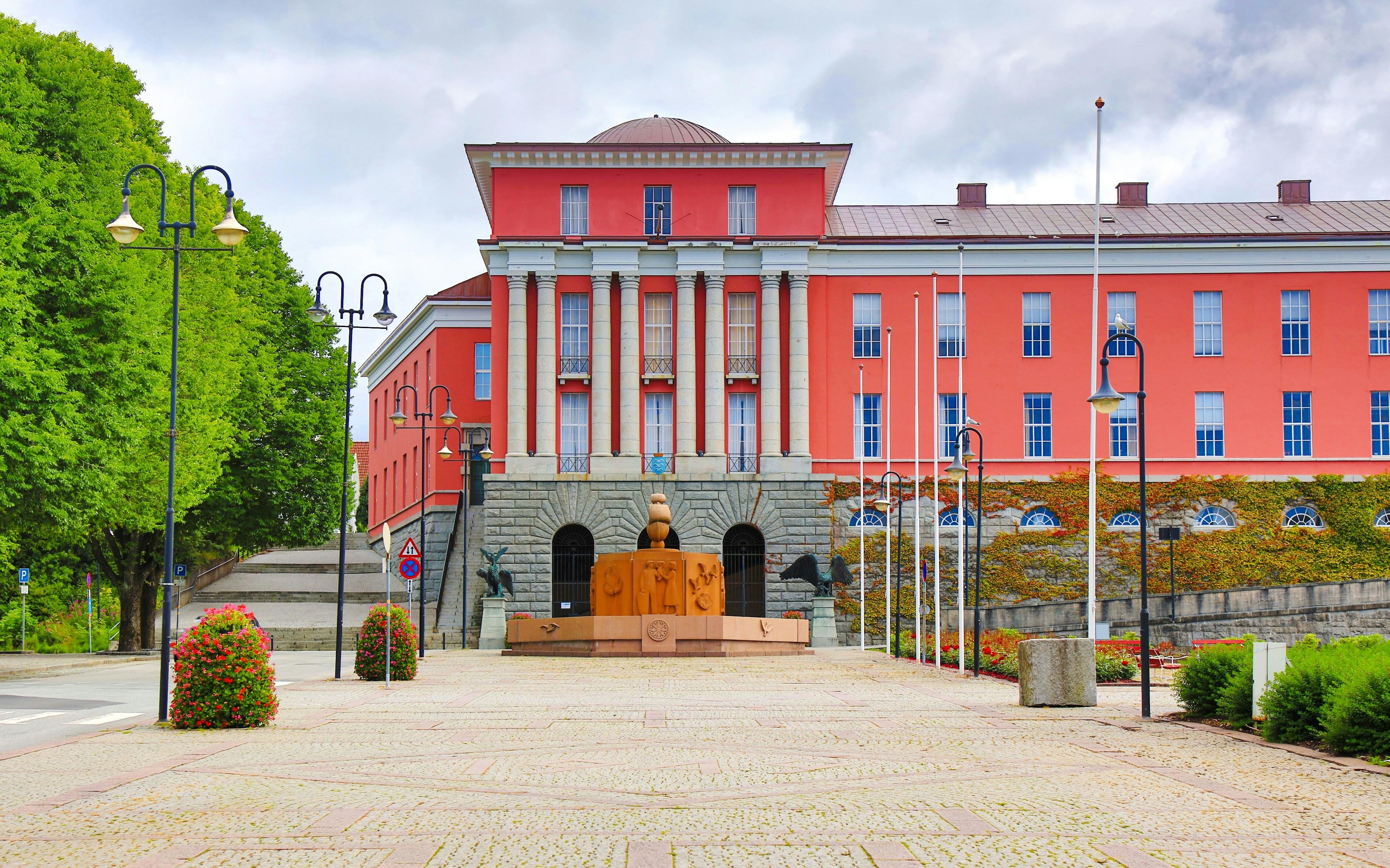 Haugesund City Hall with red facade and surrounding greenery.