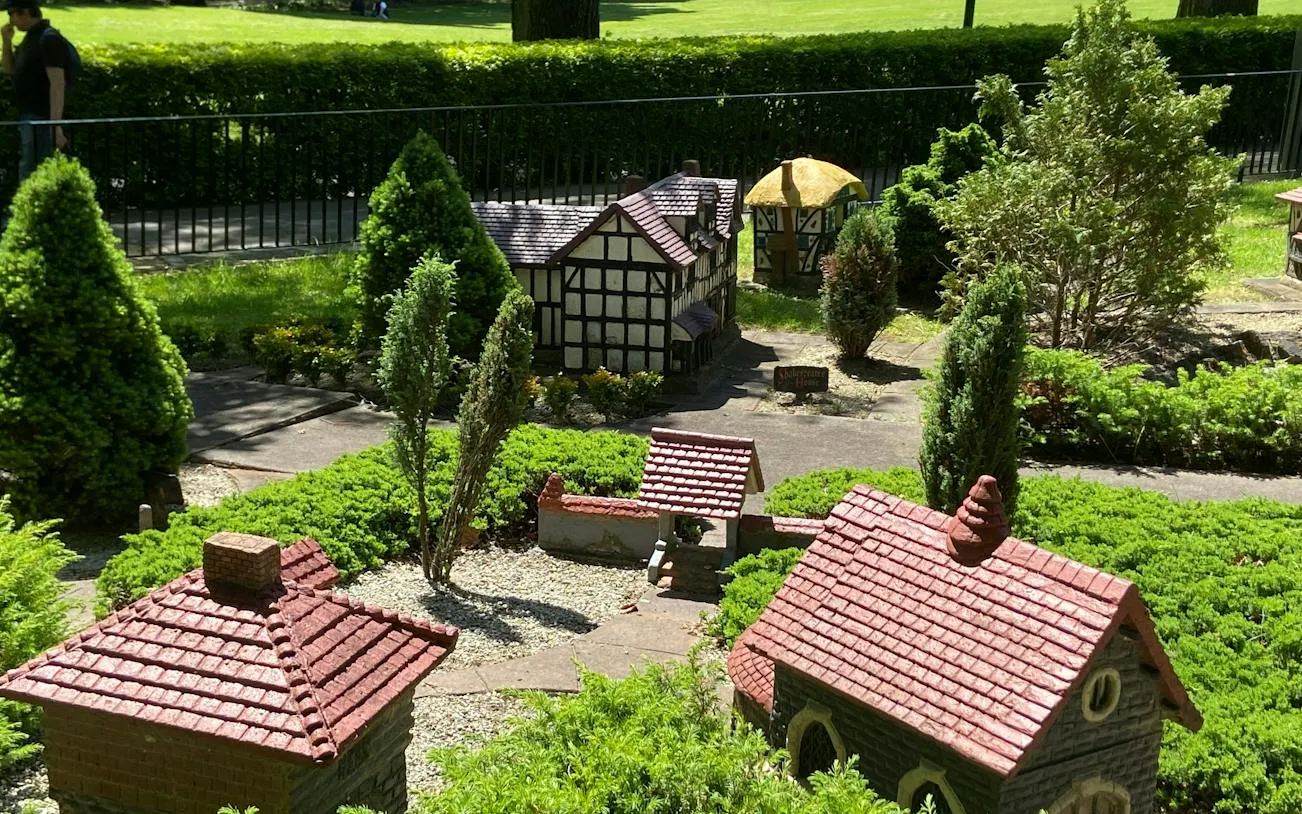 Miniature village display in Fitzroy Gardens, Melbourne, featuring model houses and greenery.