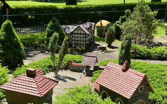 Miniature village display in Fitzroy Gardens, Melbourne, featuring model houses and greenery.
