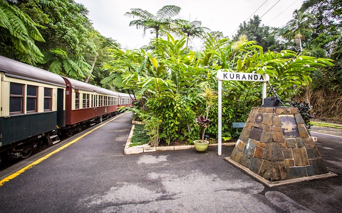 Kuranda Scenic Railway train at Kuranda station surrounded by lush greenery.