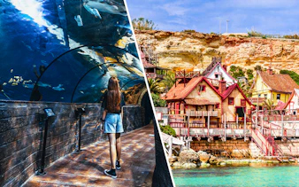 Visitor in Malta National Aquarium tunnel and colorful buildings of Popeye Village.