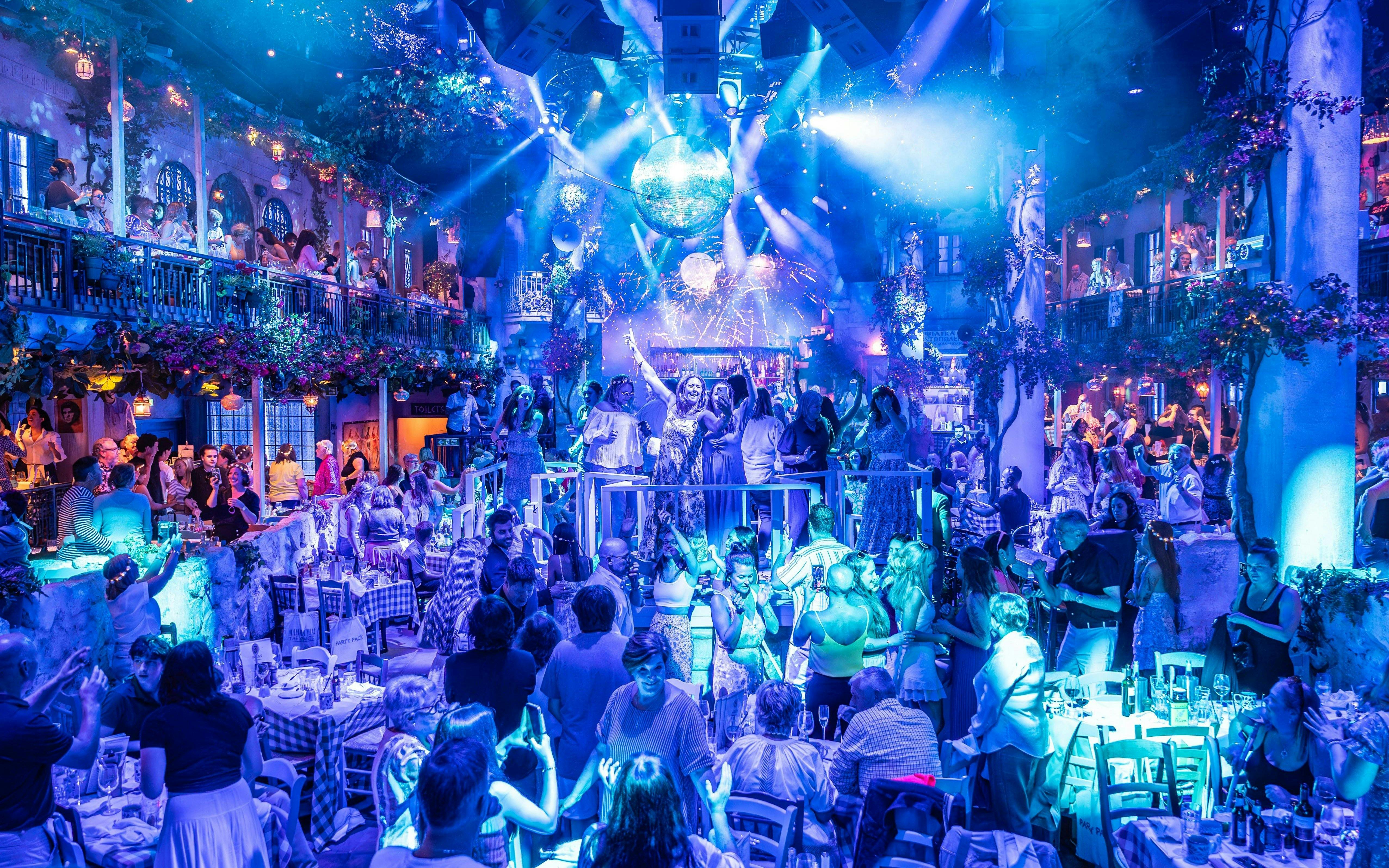 Guests enjoying Mamma Mia! The Party performance with vibrant lights and festive atmosphere.