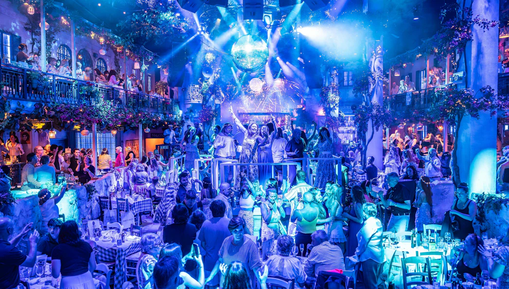 Guests enjoying Mamma Mia! The Party performance with vibrant lights and festive atmosphere.